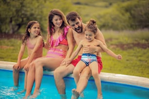 수영장 옆에 앉아 있는 행복한 가족.