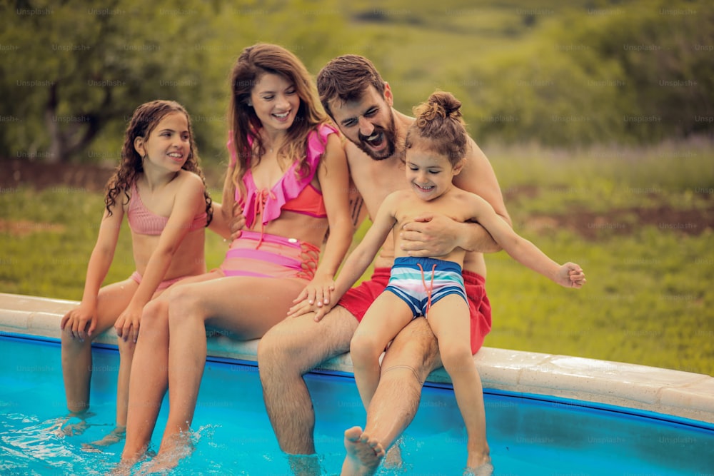 수영장 옆에 앉아 있는 행복한 가족.