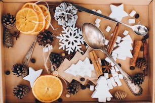 クリスマスの木の装飾、アニススター、シナモン、ドライオレンジ、松ぼっくり、スプーン、テーブルの上の箱に入ったマシュマロ。上面図。冬休みの準備。