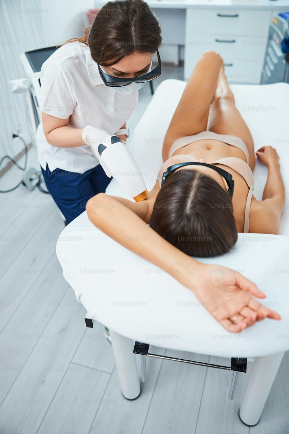 Young female having unwanted armpit hair removed by a professional cosmetologist in a beauty salon
