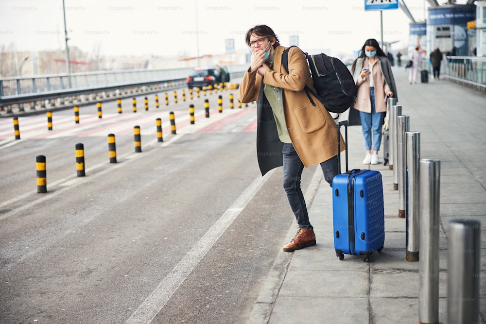 Bel signore con borsa trolley bagagli che fischia per fermare il taxi sulla strada