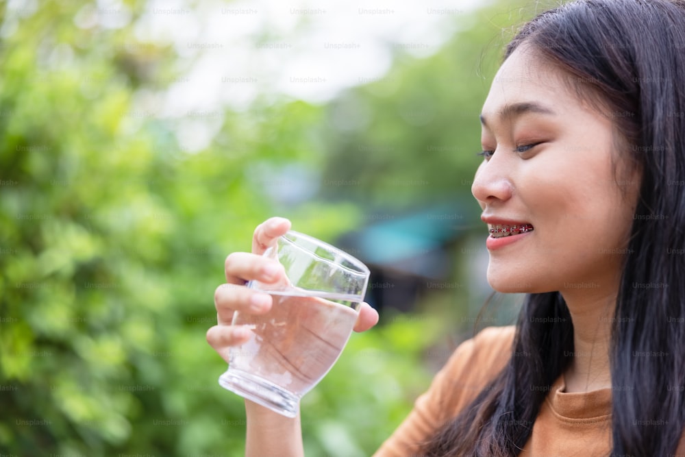 야외에서 물 한 잔을 마시는 아시아 여성의 클로즈업