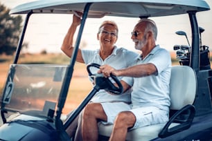 Elderly golf couple rides in a golf cart.