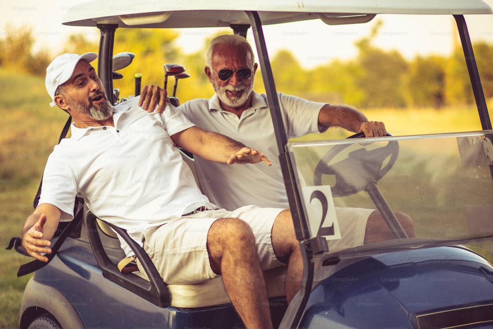 Zwei ältere Freunde fahren in einem Golfwagen.