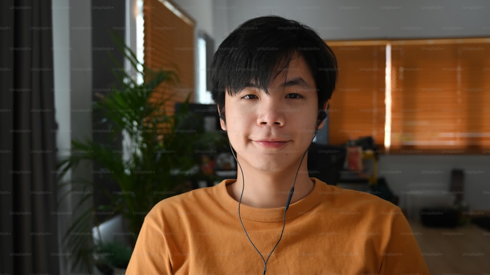 Head shot of young man wearing head phone while sitting in home office.