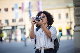 Woman in city holding vintage camera.  Woman taking photo in the city with camera.