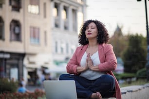 Donna d'affari afroamericana seduta in posa di loto. Donna d'affari che lavora yoga per strada.