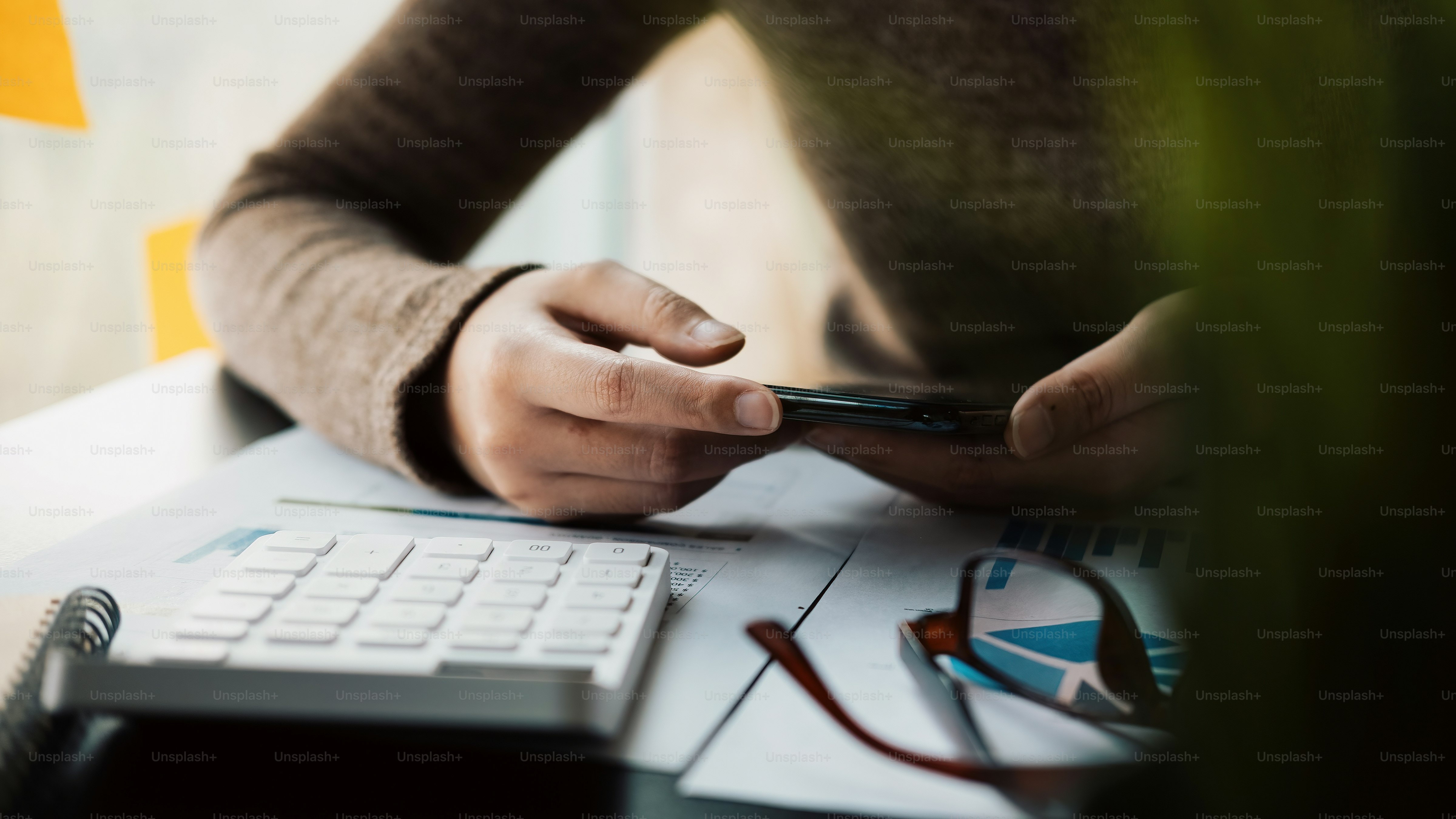 Accountant woman using smartphone calculating financial with calculator at home.