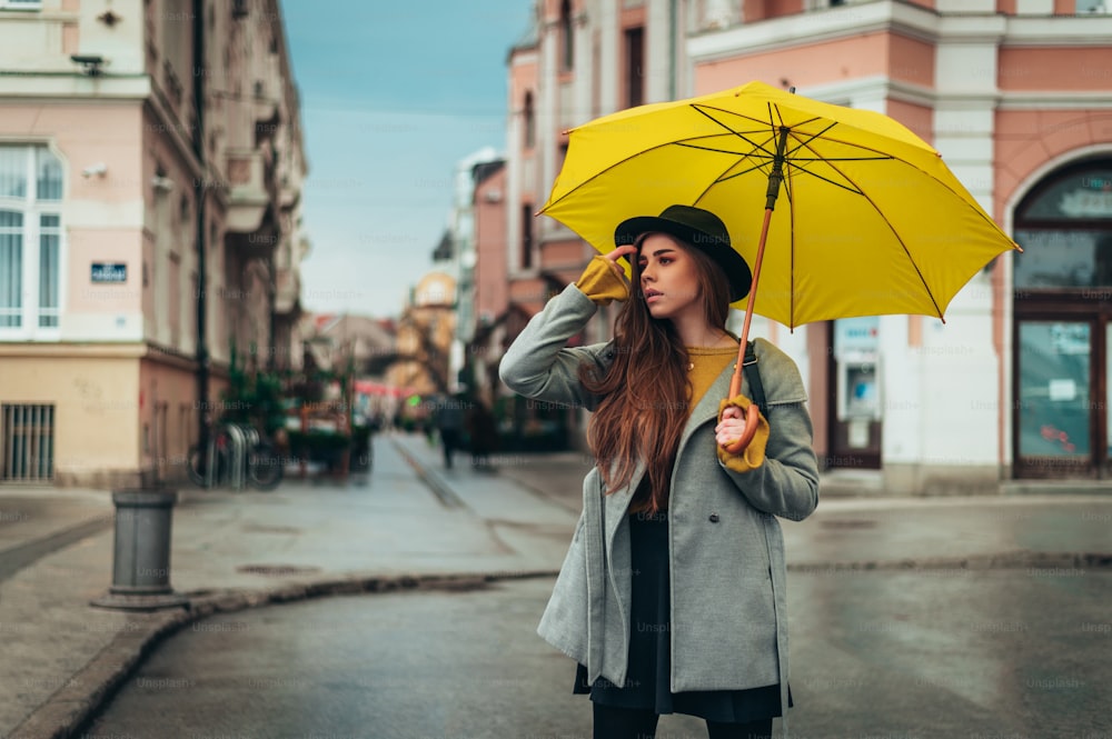 Mujer alegre en chubasquero amarillo con paraguas ríe