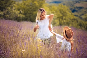 Mother and daughter dancing in lavender field.