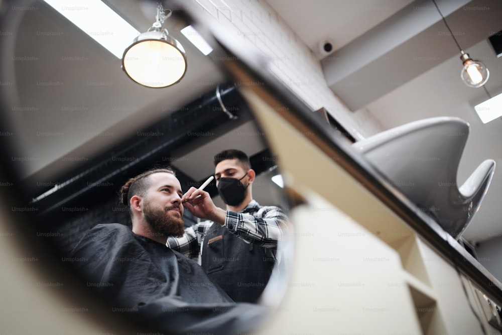 Cliente uomo in visita al parrucchiere e al parrucchiere nel negozio di barbiere, coronavirus e concetto di nuova normalità.