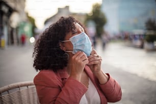 Femme avec un masque de protection assise dans un café.