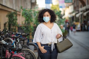 Is pandemic. Woman with protective mask on face walking trough city.