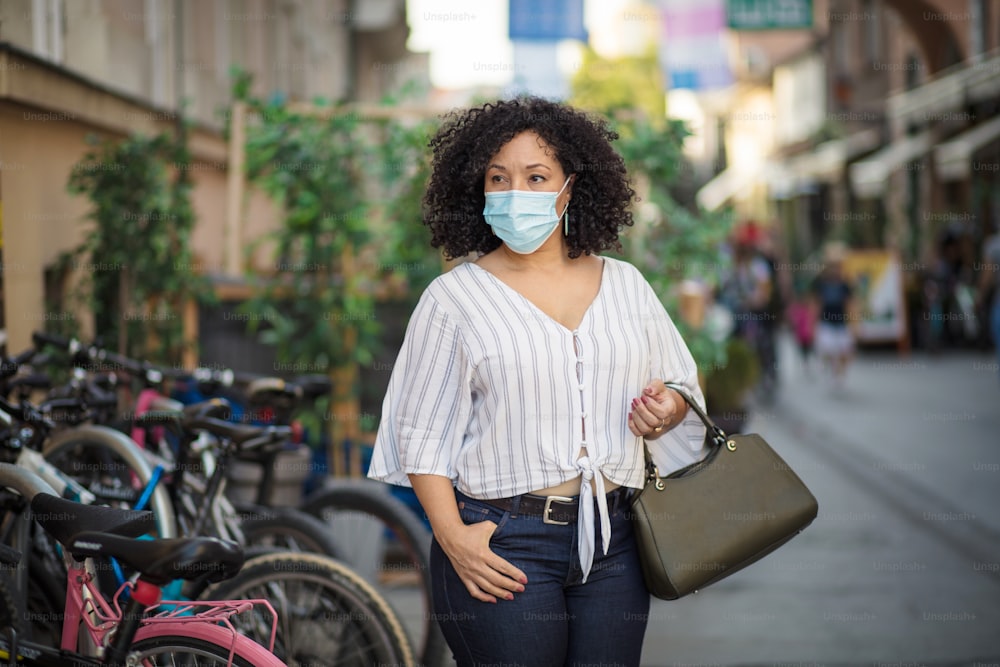 Es pandemia. Mujer con máscara protectora en la cara caminando por la ciudad.
