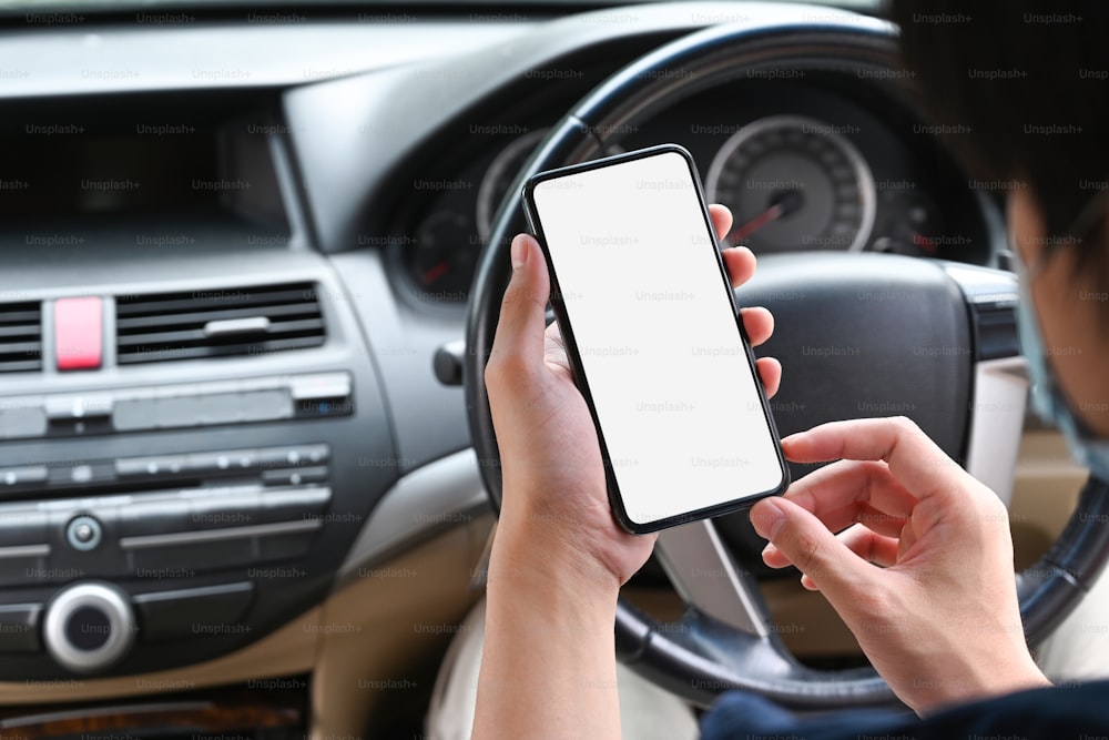 Close up view asian man holding mobile phone while sitting in car.