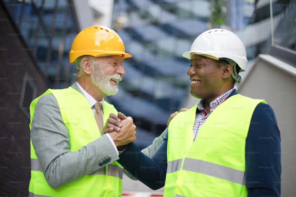 Engenheiro maduro discutindo a estrutura do prédio com colegas arquitetos no canteiro de obras.