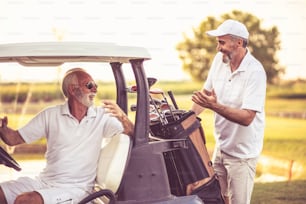 Two seniors golfer on golf court. Man sitting in golf car.