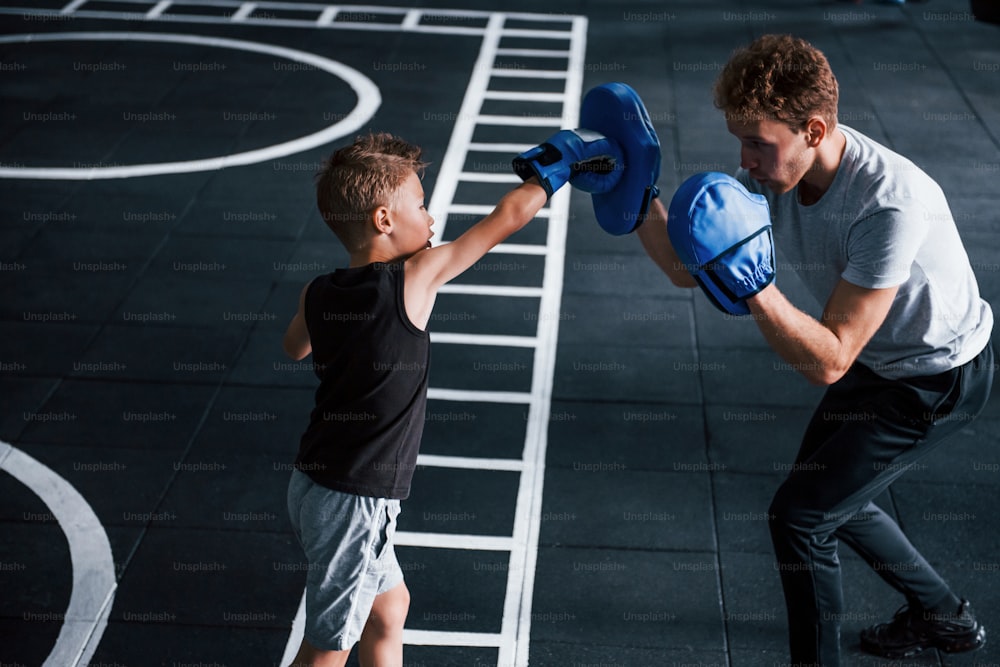 Junge Trainerin unterrichtet Kinderboxsport im Fitnessstudio.