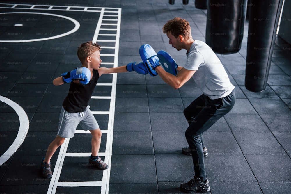 Il giovane allenatore insegna lo sport della boxe per bambini in palestra.