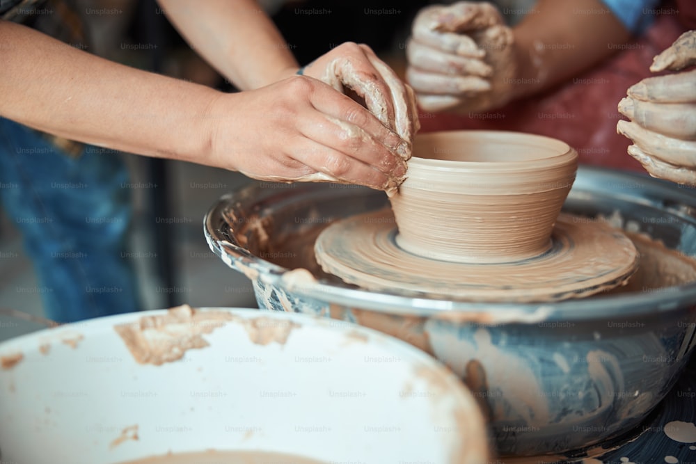Primo piano dell'artista della ceramica che modella la terracotta sul tornio di ceramica mentre lavora nello studio di ceramica