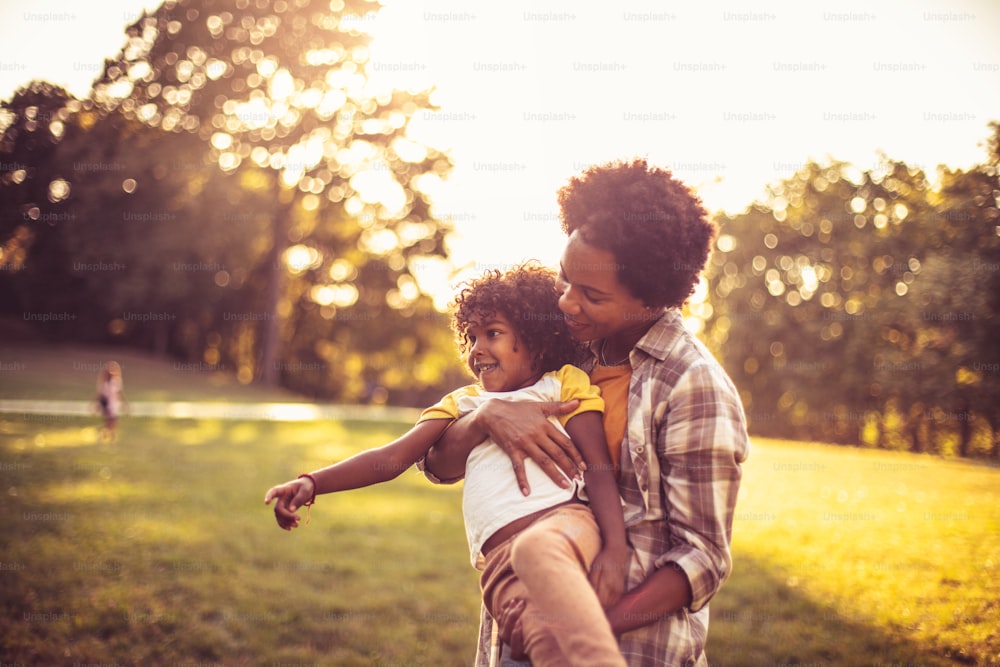 African American mother and daughter running trough park. Focus on little girl.