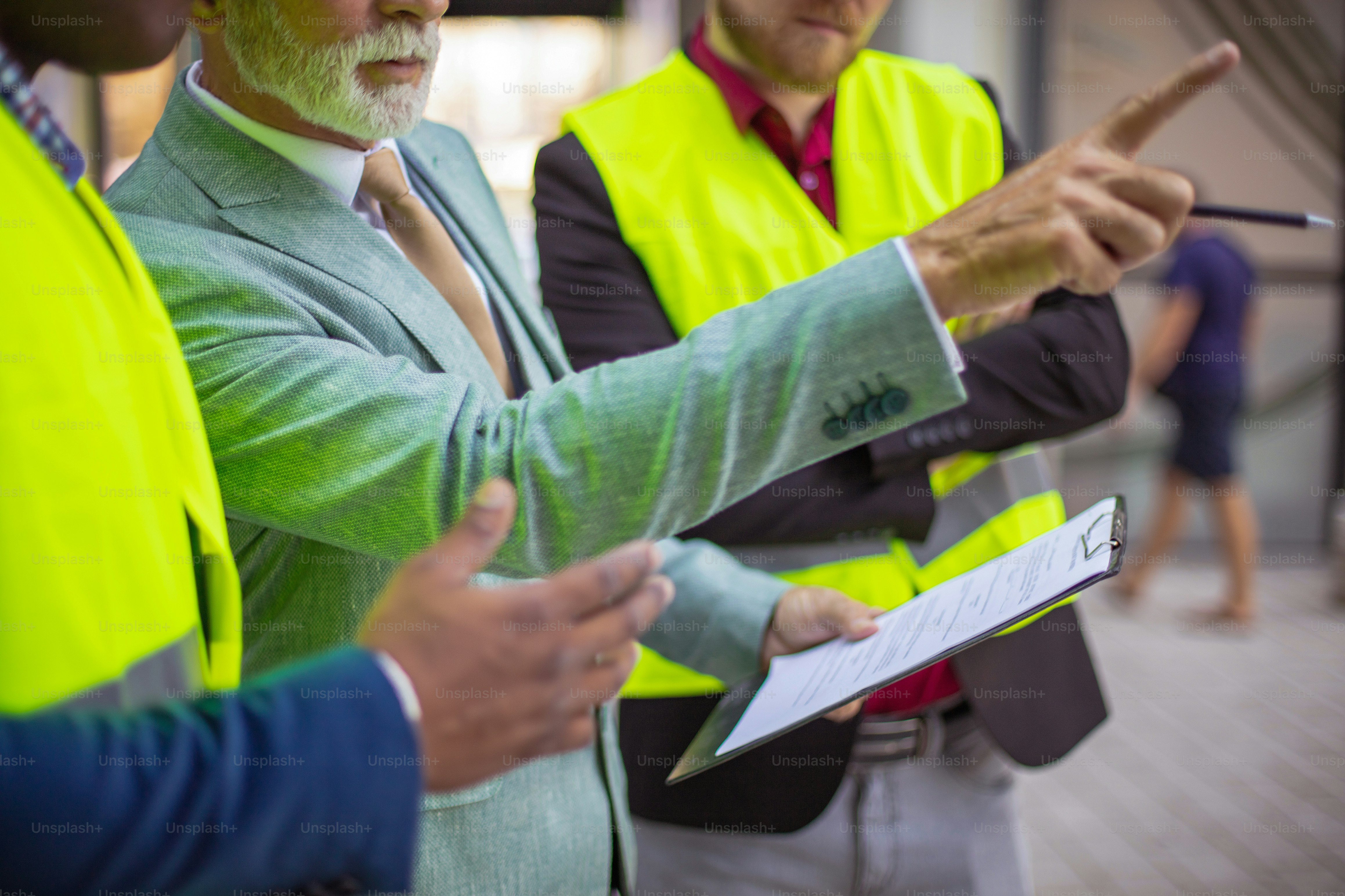 The construction site boss has a conversation with the architects. Focus is on background. Holding document
