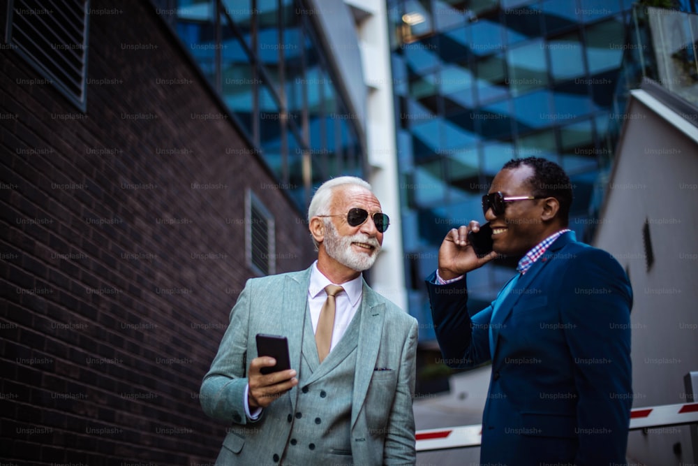Dos hombres de negocios hablando en la calle. Uso de teléfonos inteligentes.