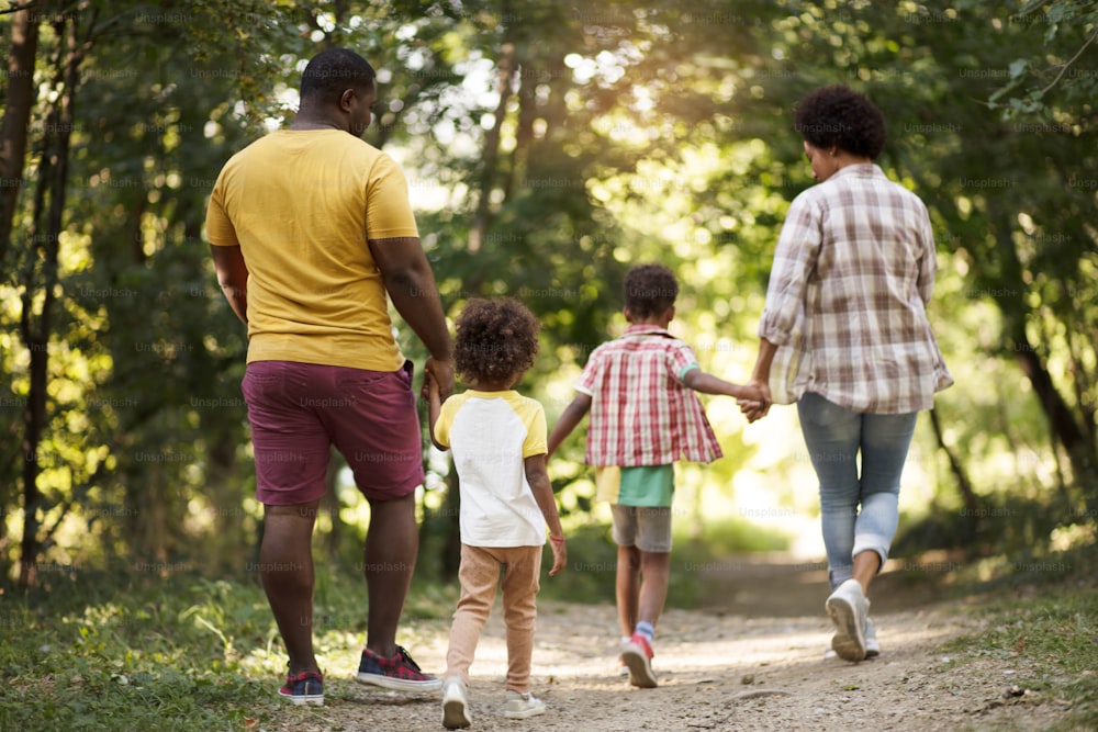 Dia da família.  Família afro-americana caminhando pelo parque.