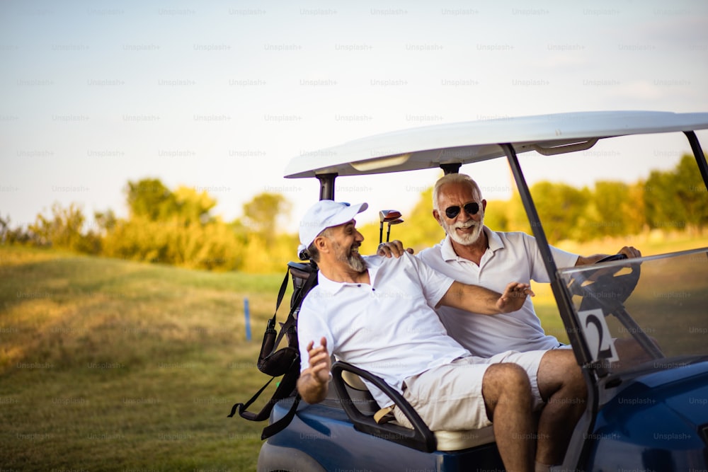 Dois amigos mais velhos estão andando em um carrinho de golfe.