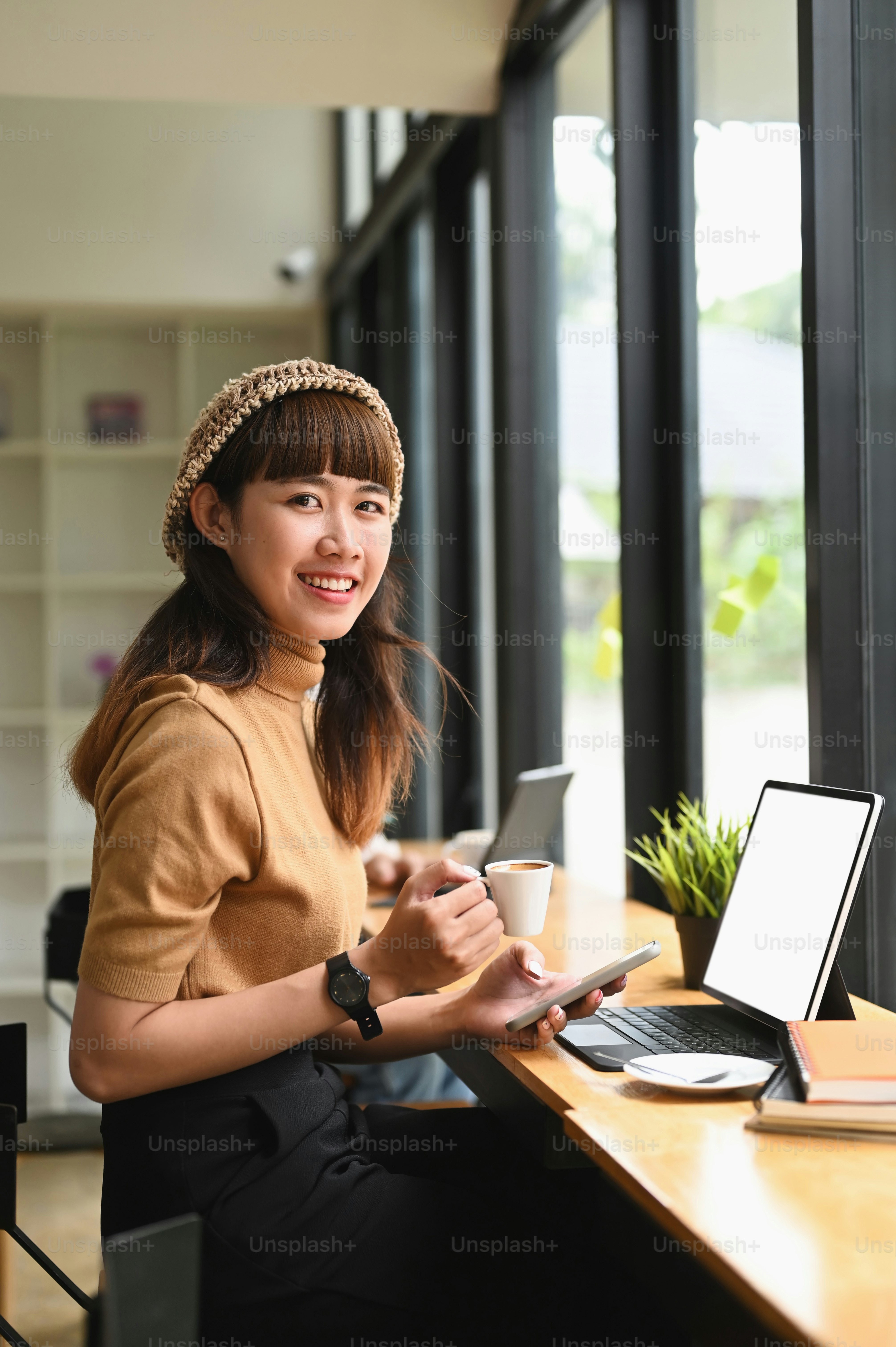 Portrait of young female sitting in modern coffee shop and smiling to ...