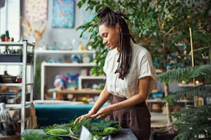 Side view of a concentrated tranquil professional female floral decorator creating a moss wall panel