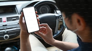 Close up view of man wearing protective mask sitting in car and using smart phone.