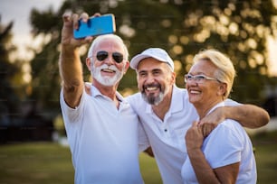 Golfistas seniores usando o telefone e tirando autorretrato.