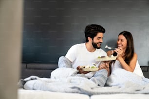 침대에서 아침 식사를 하는 로맨틱한 행복한 커플. 사랑, 사람, 음식 개념