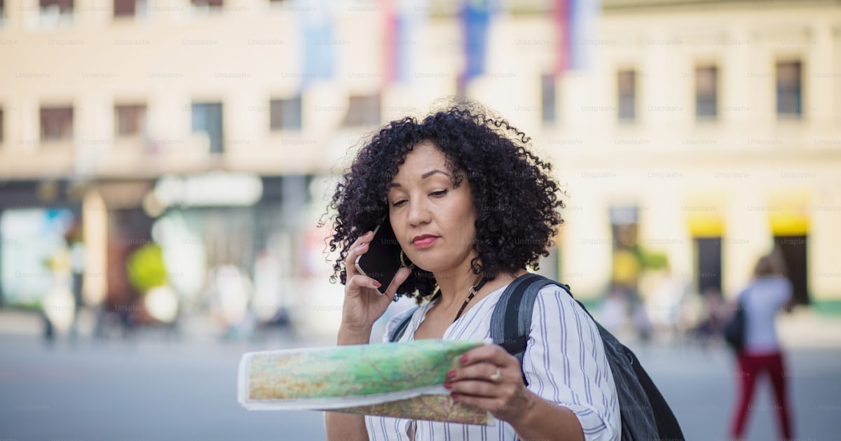 Foto Mujer de pie en la calle con el mapa en las manos y hablando por ...