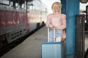 Smiling and happy woman with books.  Woman waiting on train station standing and holding books.