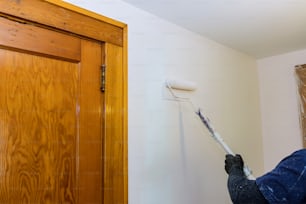 Worker painting wall in room, apartment renovation, repair home a paint roller