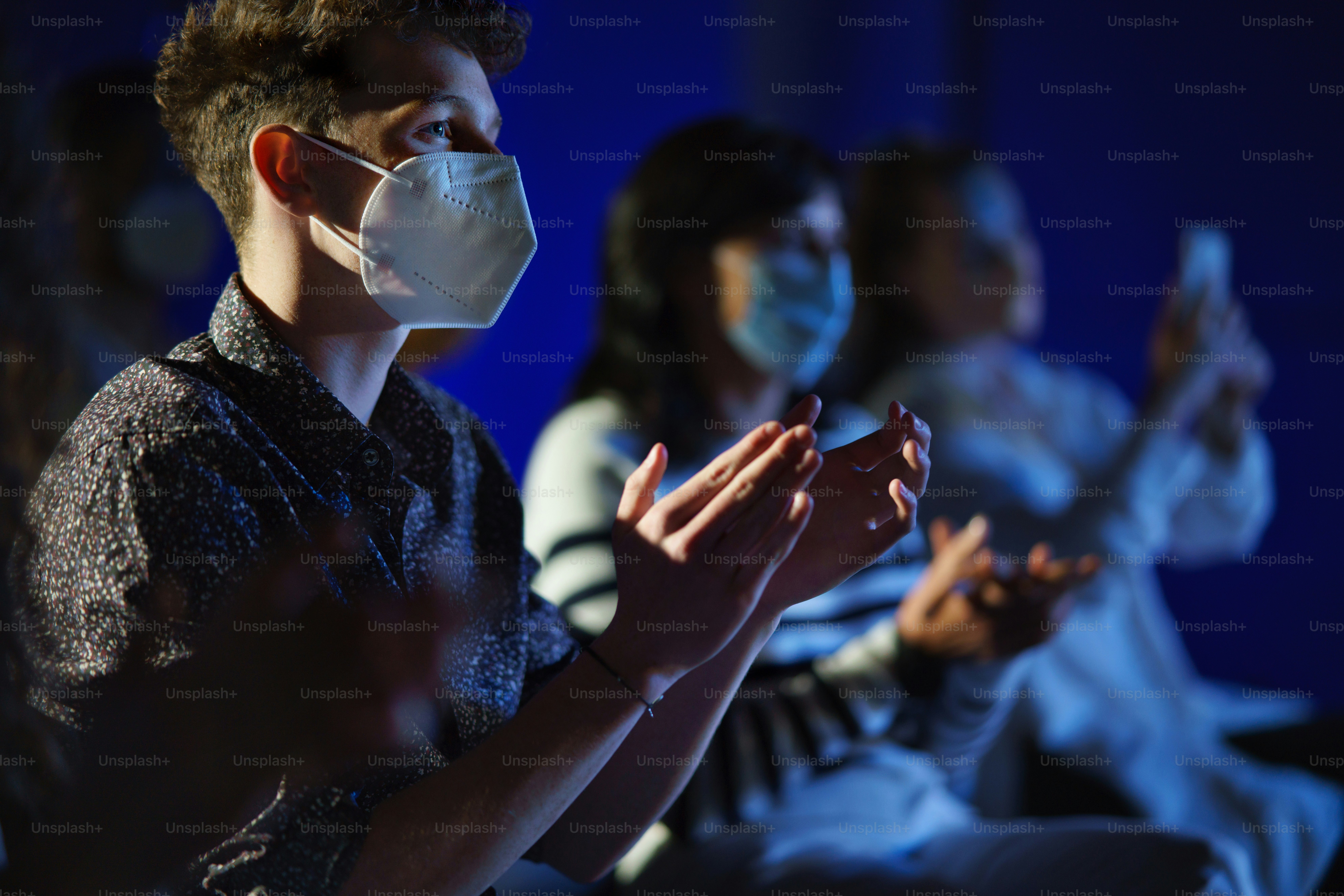 A group of people clapping while listening to presentation at conference, coronavirus concept.