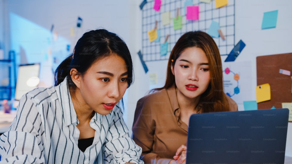 Grupo de empresários da Ásia usando apresentação de laptop computador e reunião de comunicação brainstorming ideias sobre novos colegas de projeto de trabalho plano de sucesso estratégia em casa moderna noite.