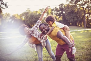 Happy black girl having fun with her parents in nature. African American family having fun outdoors.