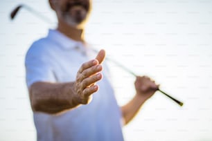 The golfer extends his hand. Focus is on hand.