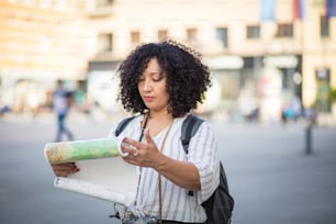 Mulher em pé na rua com o mapa nas mãos.