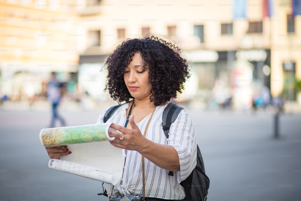Woman standing on street with map in hands.