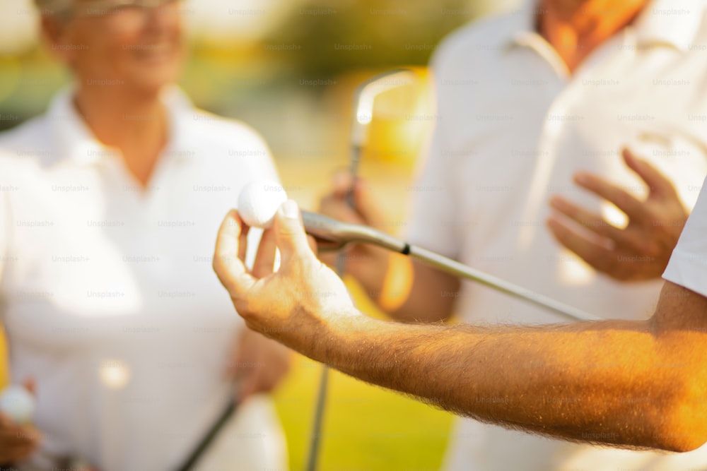 Amigos mayores en la cancha de golf hablando. El enfoque está al alcance de la mano.