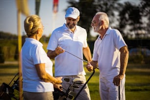 Senior friends on golf court talking.