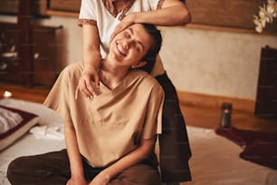 Attractive woman sitting in excitement from Thai massage of her shoulder that she getting from specialist behind her
