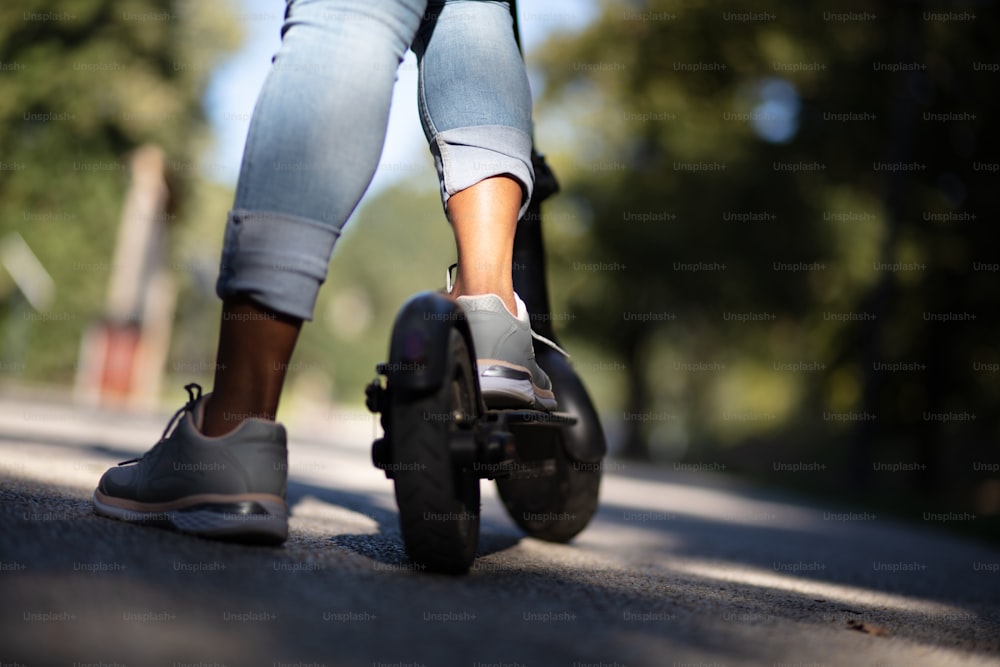 Mulheres com uma scooter elétrica no parque. Só pernas. De perto.
