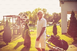 Senior man walking with golf bag.