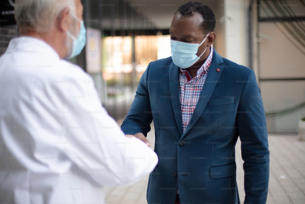 Business man, and doctor on street handshaking.