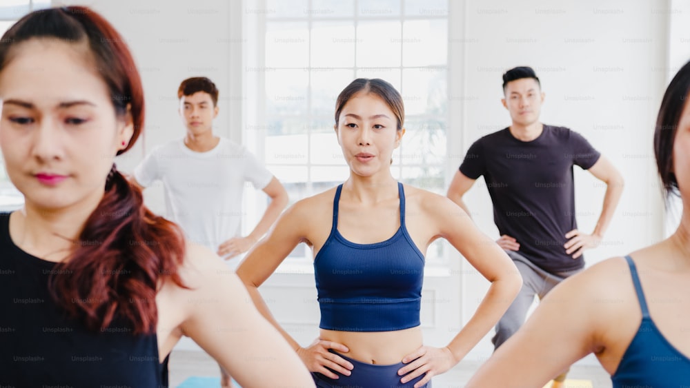 Jóvenes asiáticos deportistas atractivos practicando clase de yoga con instructor. Grupo asiático de mujeres que ejercen un estilo de vida saludable en un gimnasio. Actividad deportiva, gimnasia o clase de ballet.